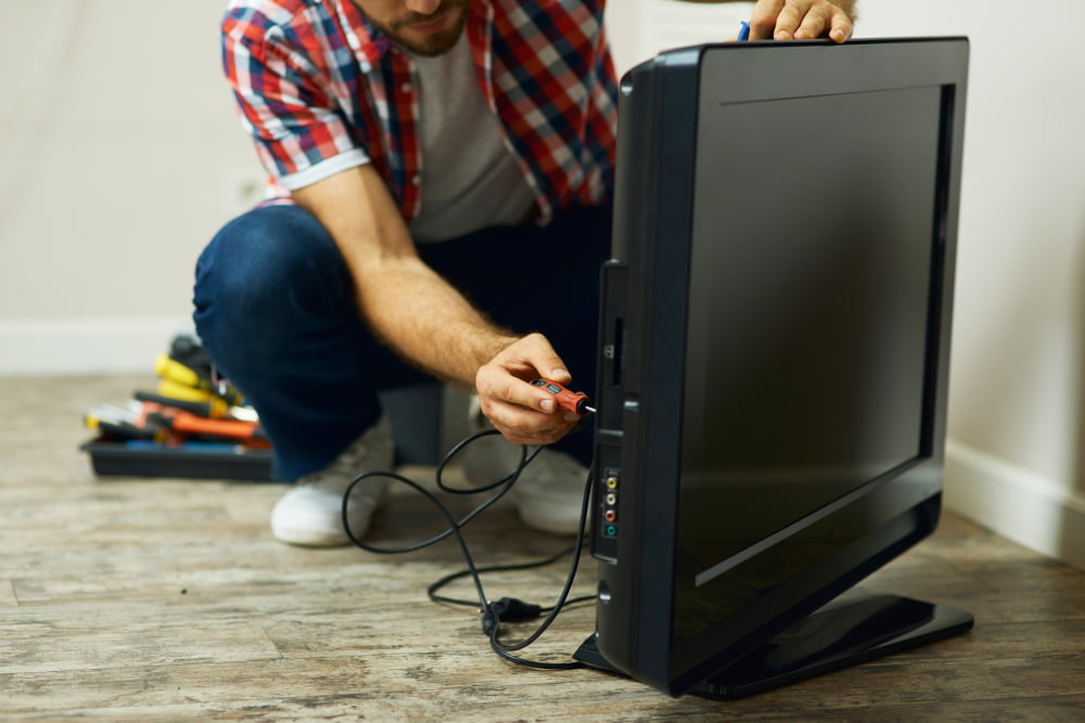 appliance-service-cropped-shot-repairman-using-screwdriver-while-installing-fixing-tv-set